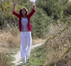 happy aging woman jumping for wellbeing in countryside