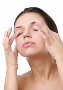 Young woman pushes with fingers on closed eyes. Isolated over white.