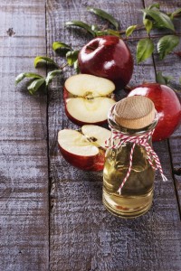 Apple cider vinegar and apples over white wooden background