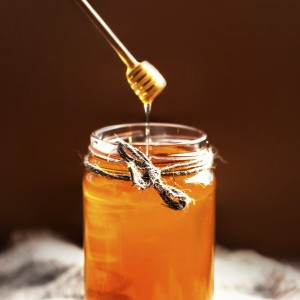 Fresh Honey in jar with honey flowing dipper on rustic wooden background close